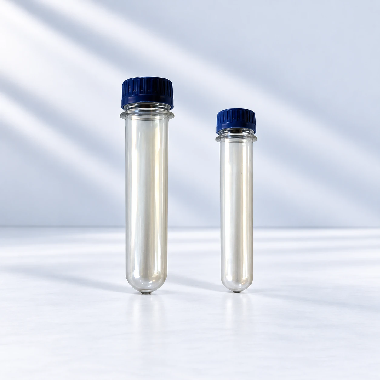 Two clear PET preforms of different lengths with dark blue caps